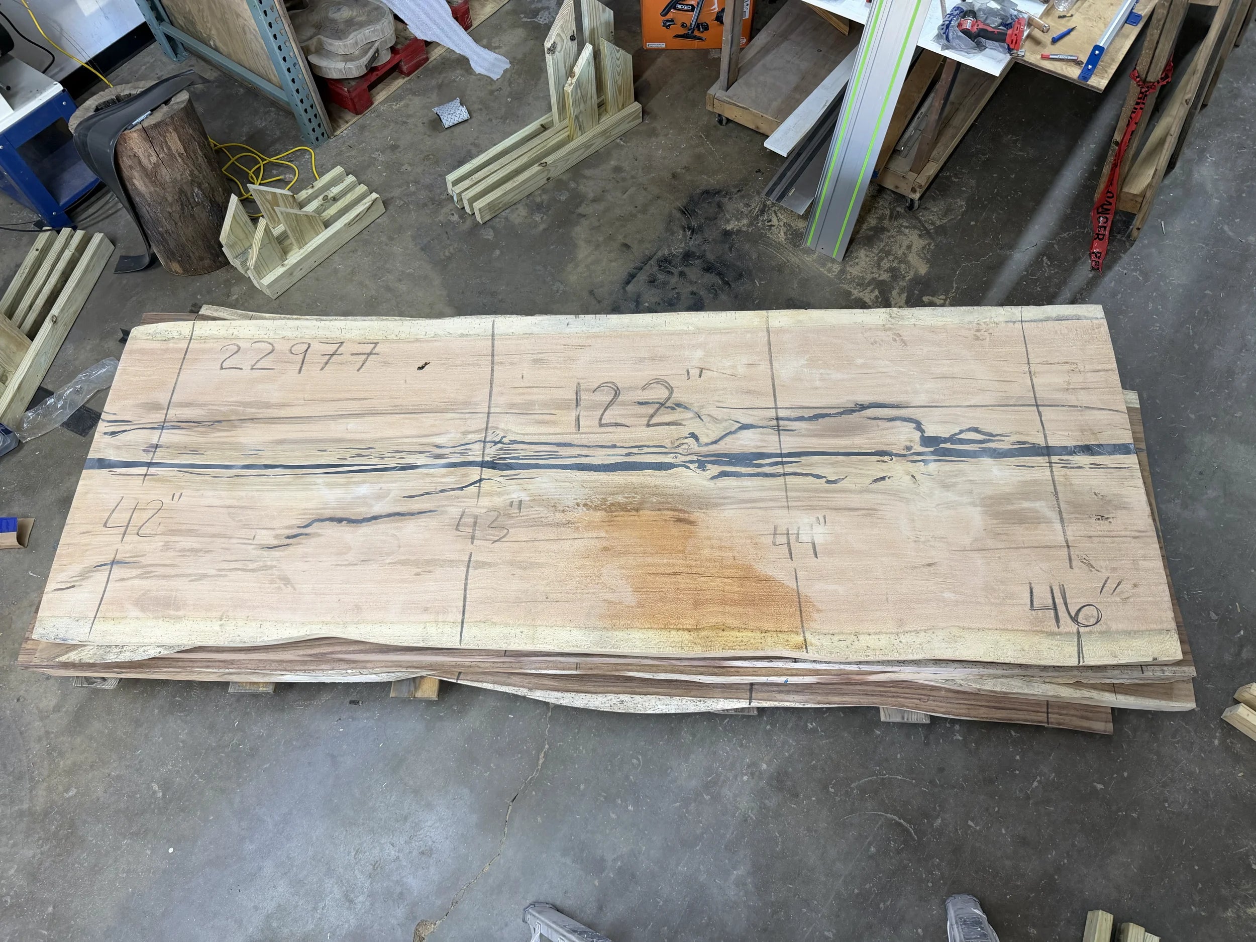 Large wooden slab with measurements on a workshop floor