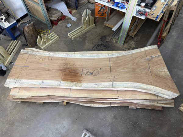 Stack of wooden table slabs on a workshop floor