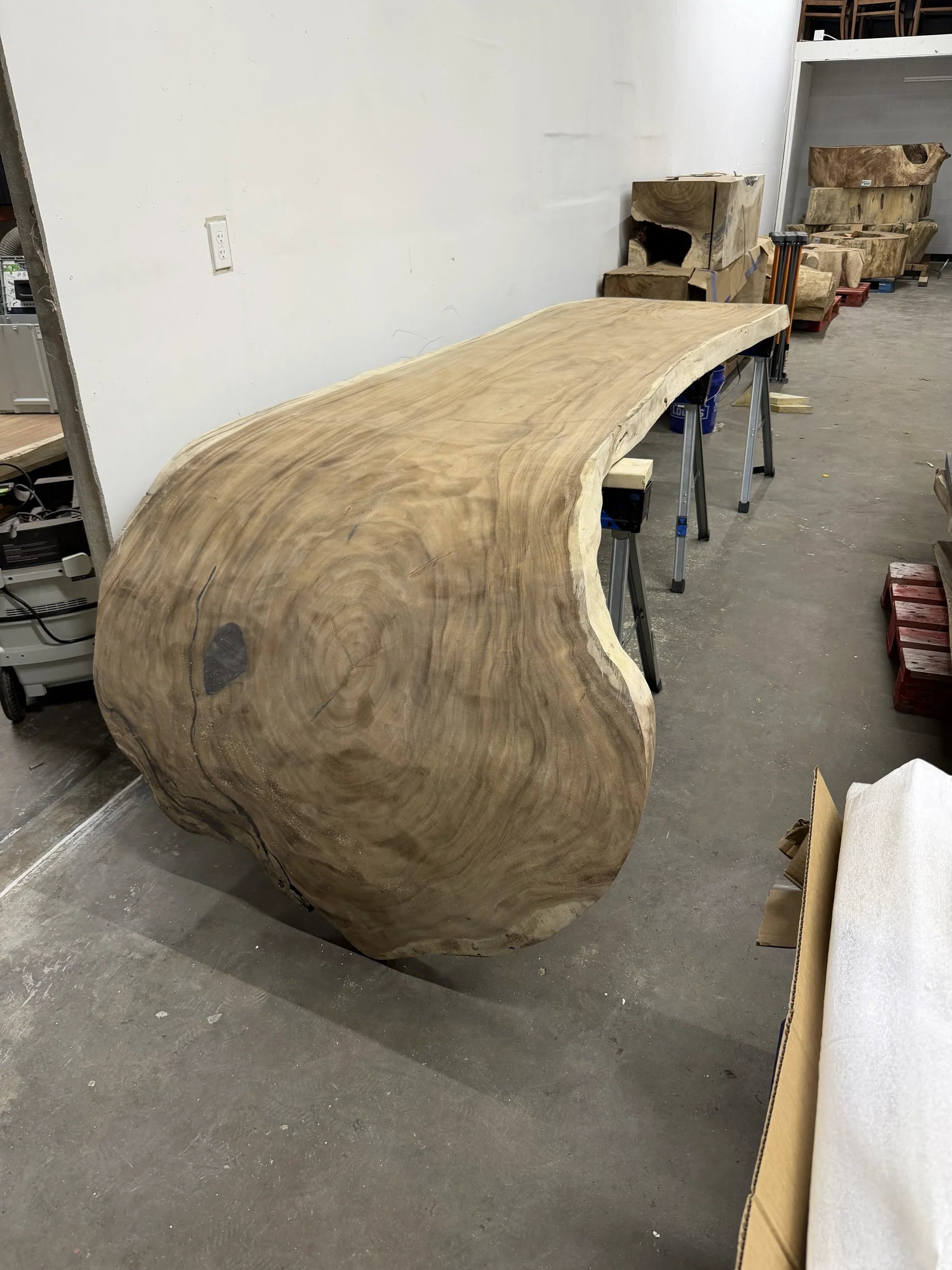 Wooden sculpture or piece of furniture on a concrete floor with tools and materials in the background.
